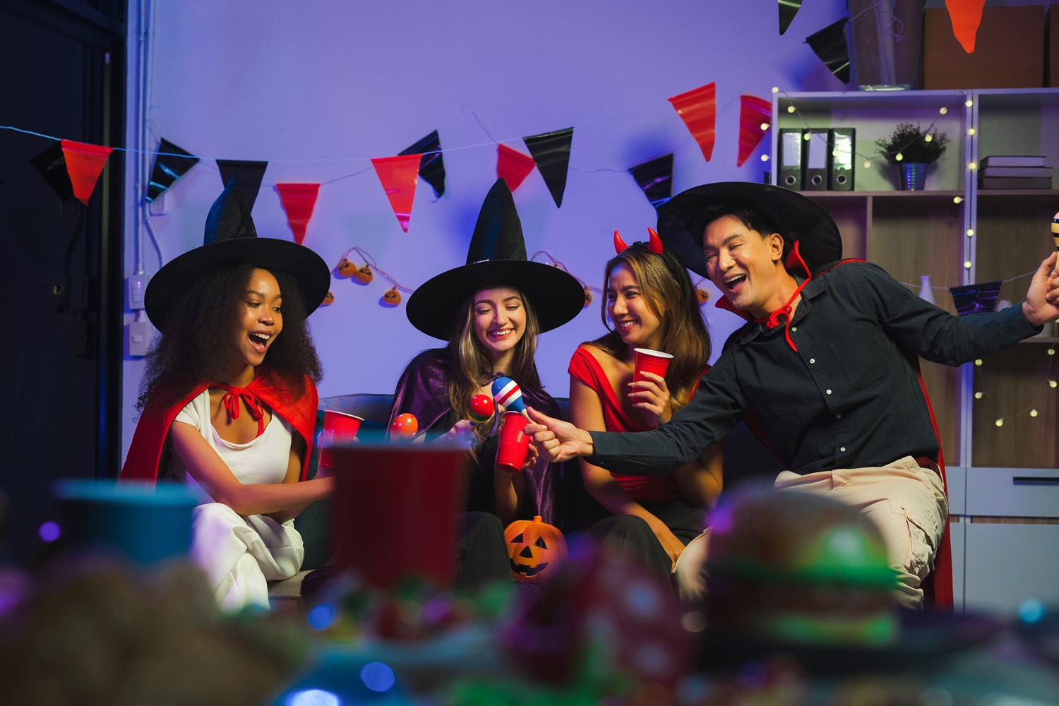 Dinner and group of people celebrating together at Halloween party. Friends are happy and celebrating with food, wine and friendship of love and cheers of champagne at the event.